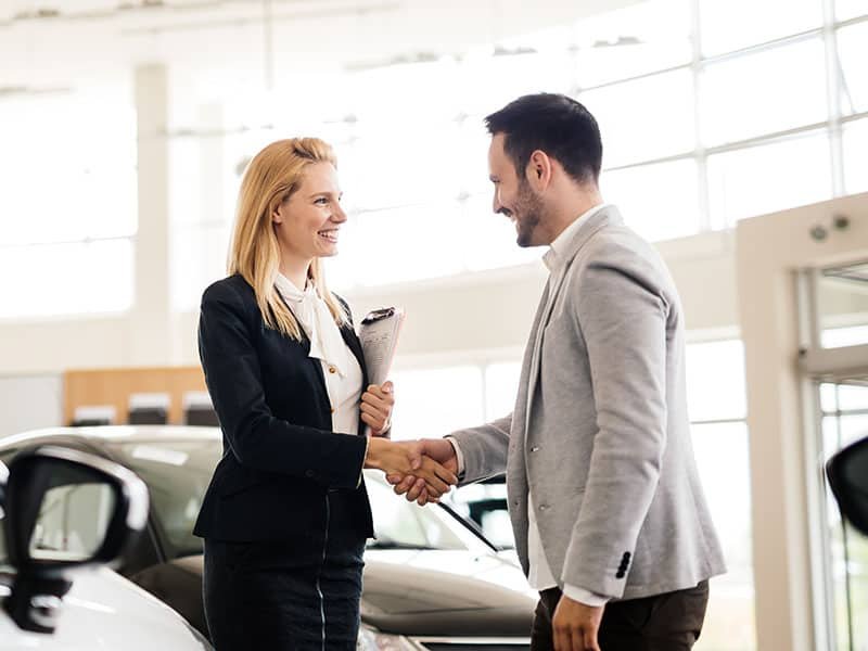 Salesperson showing vehicle to potential customer in dealership